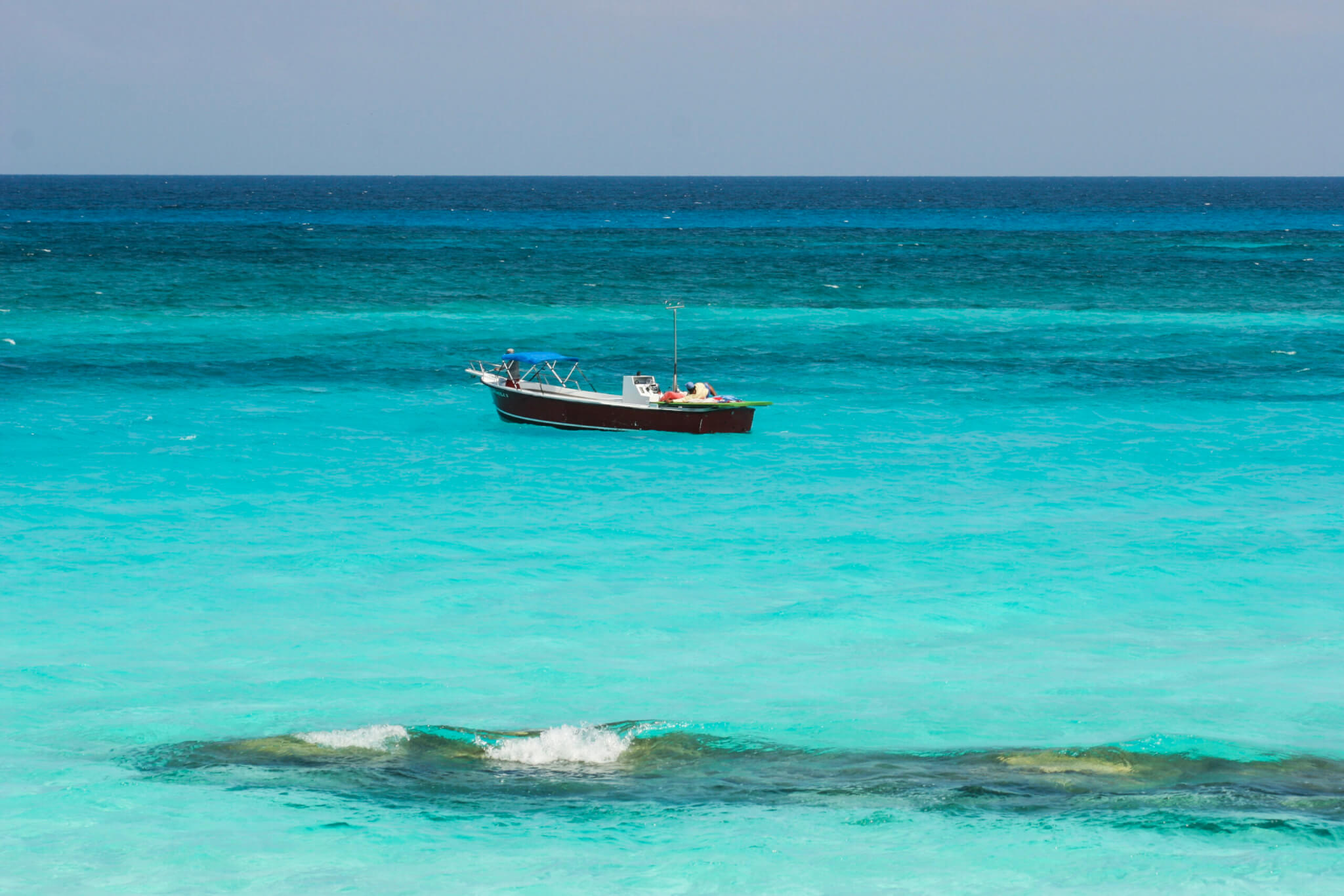 Small fishing boat out in beautiful clear turquoise water in Barbados