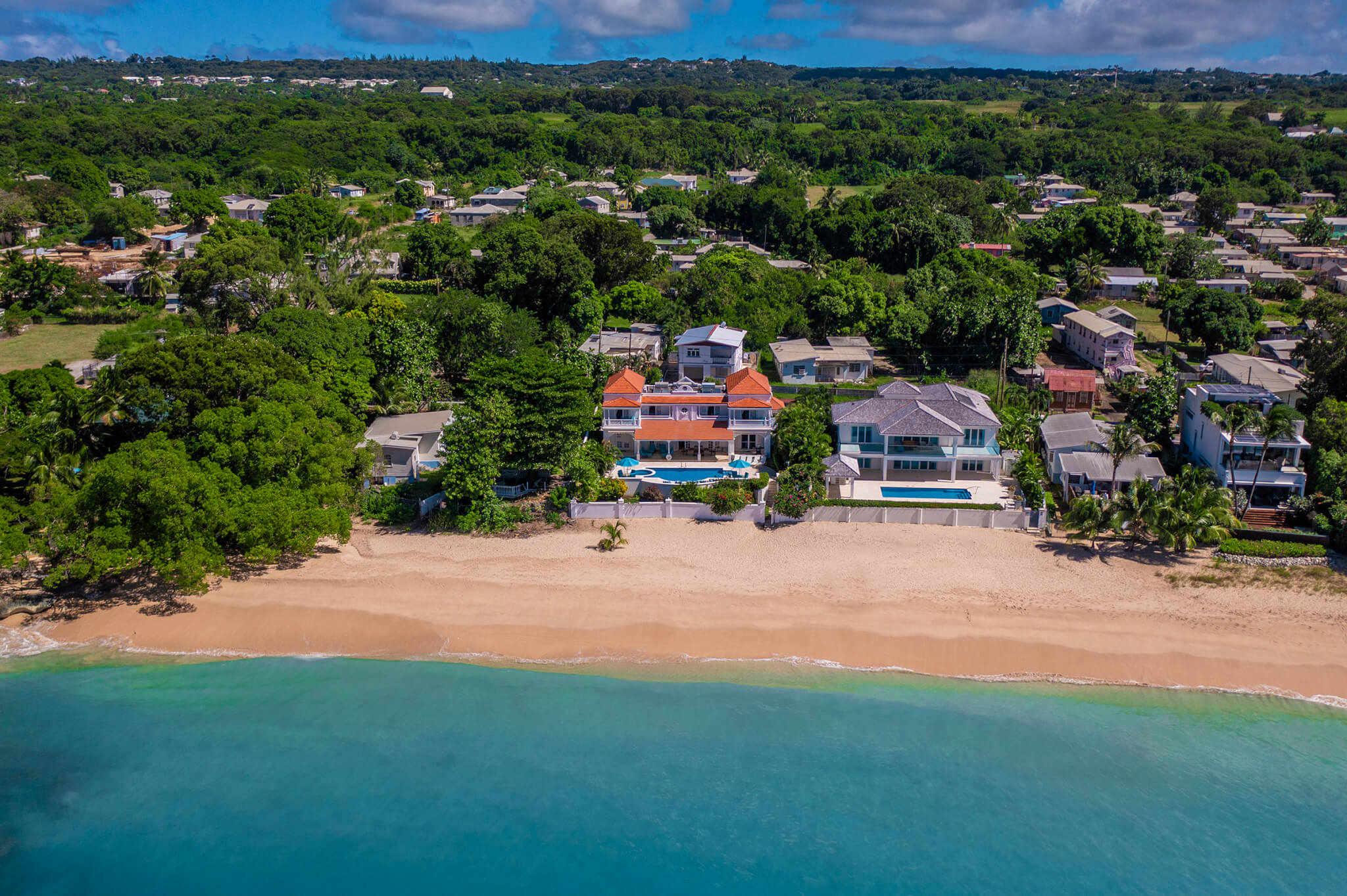 Ariel shot of a couple houses right on the beach front with turquoise waters