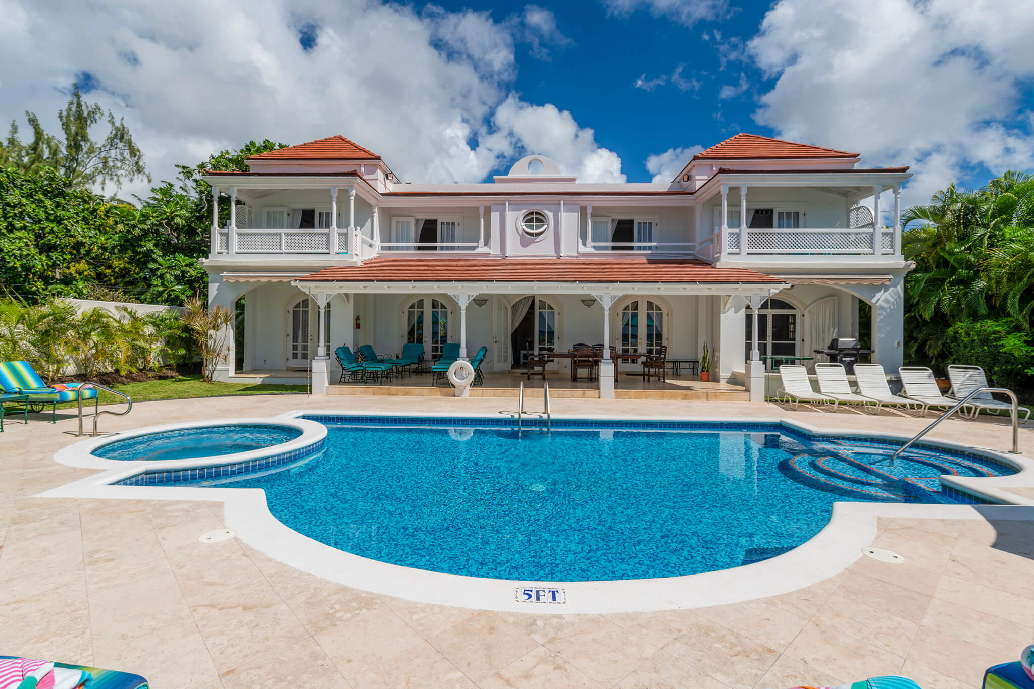 Looking over the pool and back at the large symmetrical house with a tiled roof