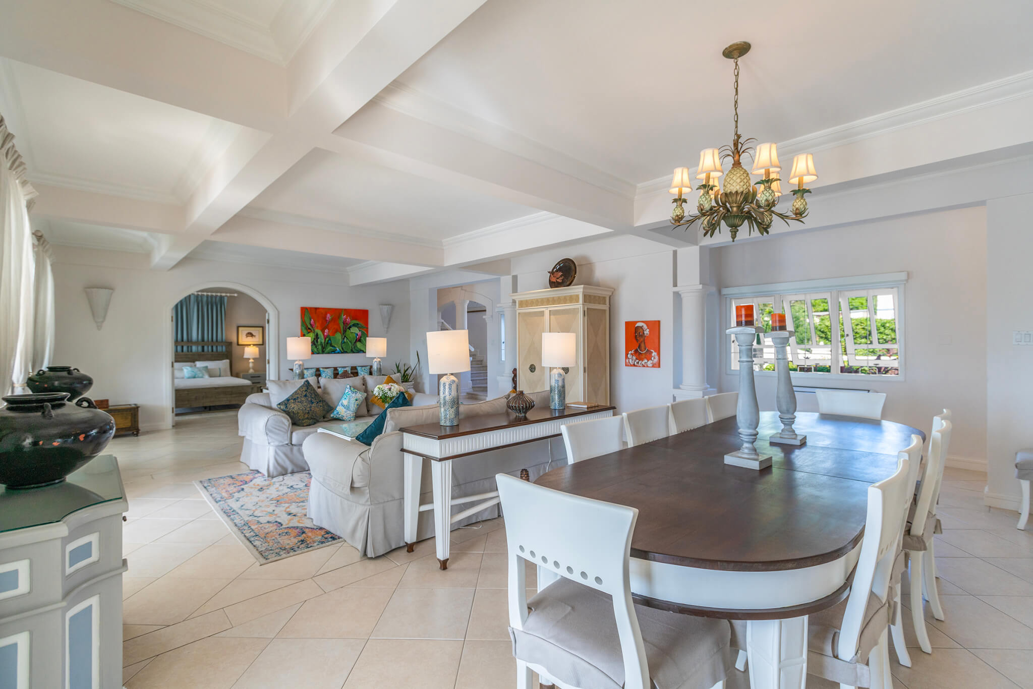 Large open plan dining and lounge area with a hanging light feature over the long dining table and a luxurious Persian rug under the lounges