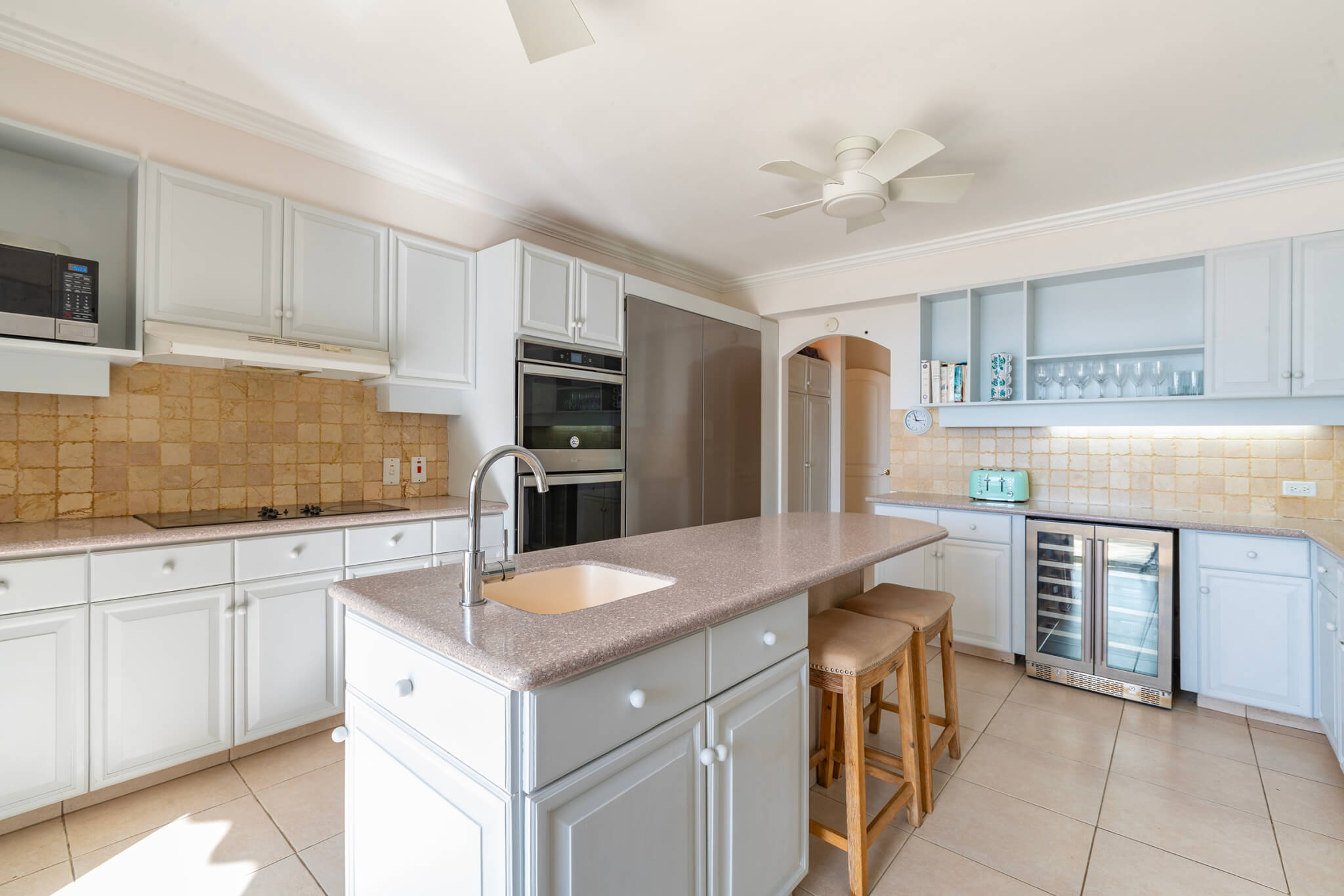 Modern kitchen with an island/breakfast bar. white cupboard doors and a large stainless steel fridge